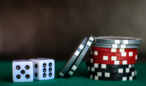 Two dice and a stack of colorful casino chips on a green surface